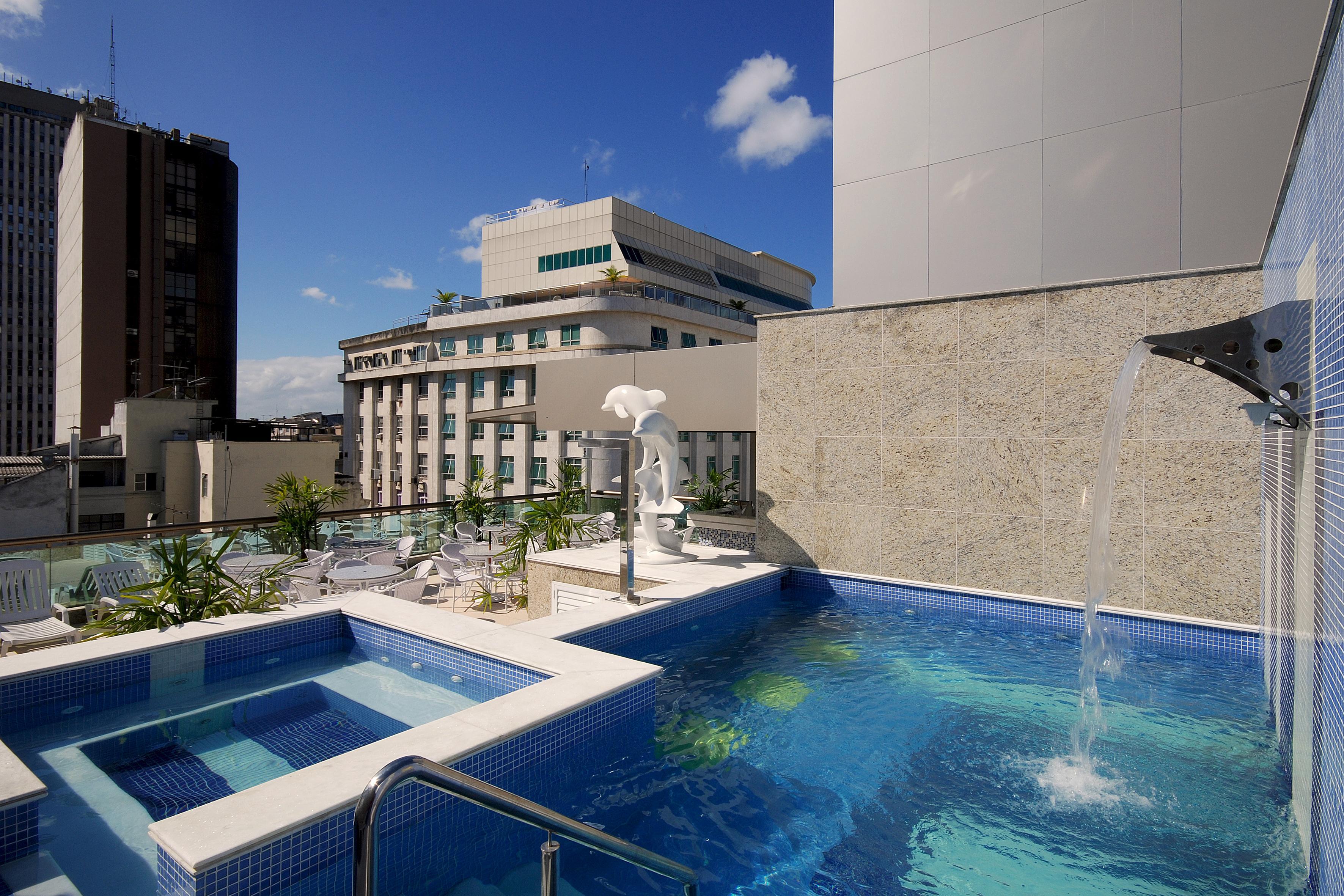 Hotel Atlantico Business Centro Ρίο ντε Τζανέιρο Εξωτερικό φωτογραφία The photo shows a rooftop area featuring a swimming pool and a spa. The pool is inviting with a clear blue water, and there appears to be a waterfall feature. Surrounding the pool are areas for relaxation, possibly with sun loungers. In the backgroun